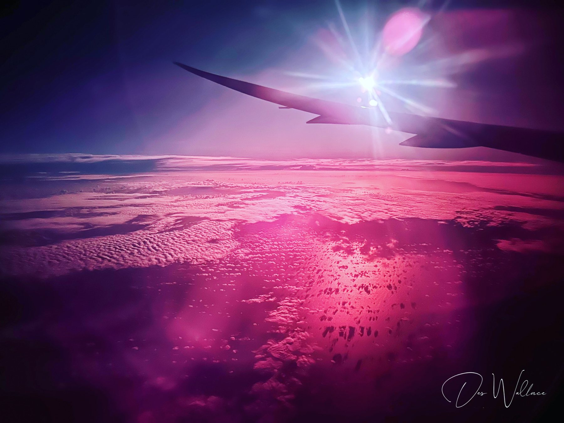 Airplane wing at altitude against a pink sky — perspective, distance, and the long view
